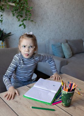 Açık tenli, çizgili siyah beyaz balıkçı yaka ve şeffaf gözlük takan genç bir kız. Sinirli ya da sinirli görünüyor. Muhtemelen bir çalışma ya da ödev sırasında.