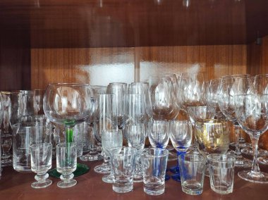 Ahşap bir vitrinde farklı boyutlarda çeşitli kristal bardaklar ve bardaklar.