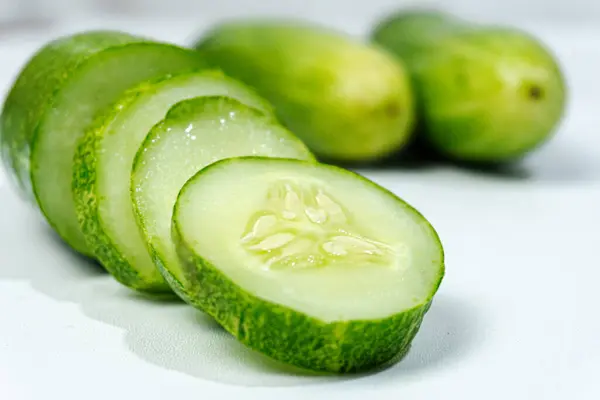 Taze yeşil salatalık ve salatalık. Beyaz arka planda düzenlenmiş ve biçilmiş. Salatalıklar K vitamini, C vitamini, potasyum ve magnezyum gibi önemli vitamin ve mineraller içerir..