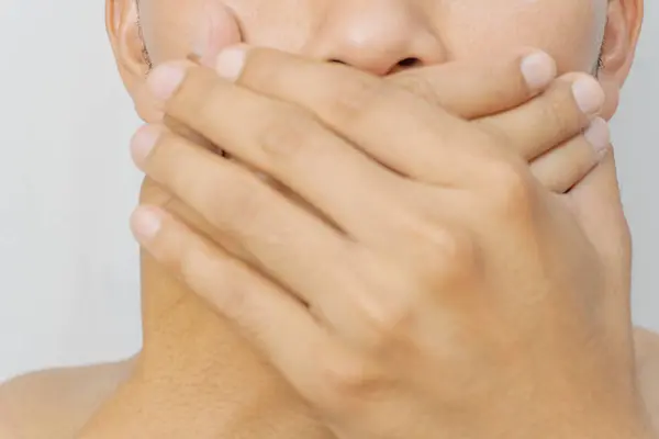 Görüntü, elini ağzını kapatan bir kişiyi gösteriyor. Gizlilik, sessizlik ya da bastırma hissi veriyor. Konuşma özgürlüğünü sınırlama kavramı