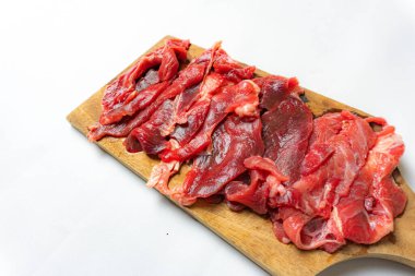 Kesme tahtasında servis edilen dilimlenmiş çiğ et beyaz arka planda izole edilmiş.