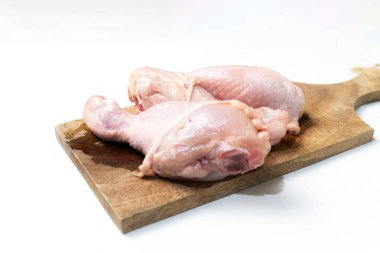 Beyaz arka planda izole edilmiş kesme tahtasındaki taze çiğ tavuk budu..
