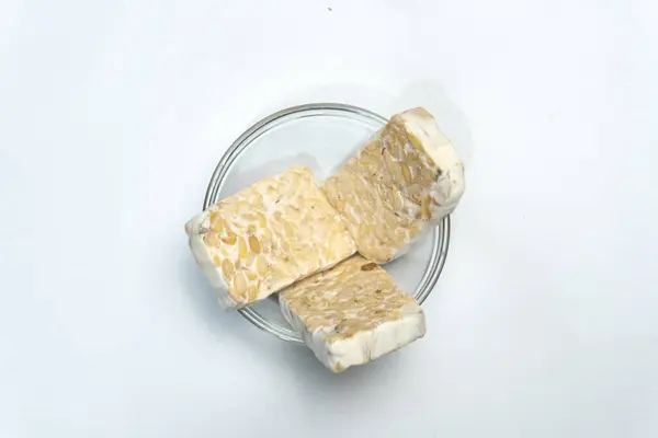 Endonezya Tempe 'si ya da mayalanmış soya fasulyesi. Beyaz arka planda mayalanmış soya fasulyesinin geleneksel yiyeceği. Geleneksel Endonezya Tempe Çanağı. Taze Tempeh Hazır