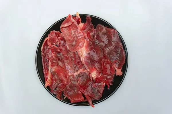 Dilimlenmiş taze et, siyah tabakta servis edilir. Izgara için beyaz izole edilmiş.. 