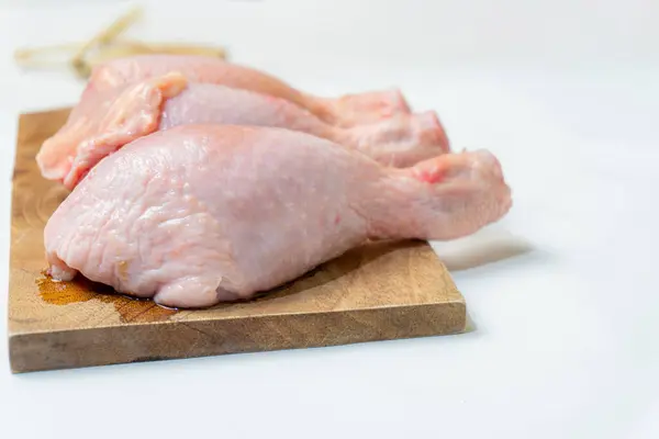 Beyaz arka planda izole edilmiş kesme tahtasındaki taze çiğ tavuk budu..