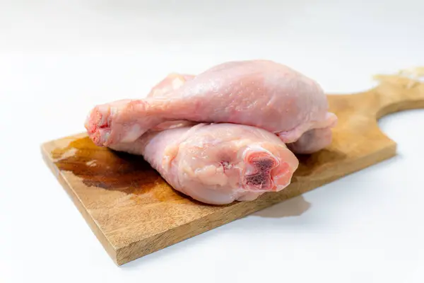 Beyaz arka planda izole edilmiş kesme tahtasındaki taze çiğ tavuk budu..