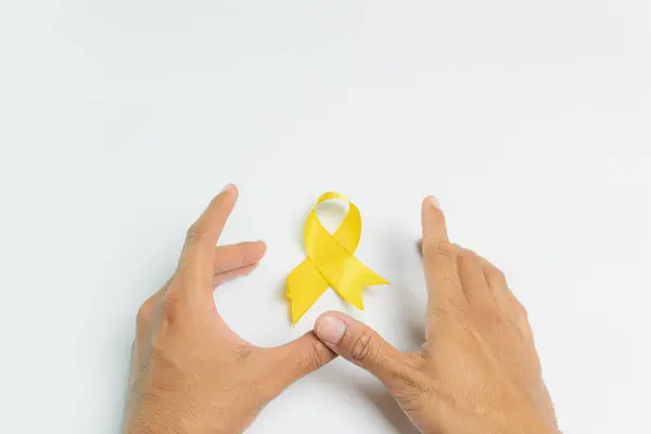 El ve sarı kurdele intihar önleme hareketinin sembolü olarak, beyaz arka plan, intihar önleme ve çocukluk kanseri farkındalığı, Dünya İntihar Önleme Günü konsepti.