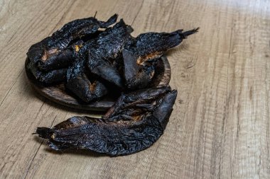 smoked catfish on a wooden plate. The fish are dark brown in color and have a rough texture. The plate is also made of wood and has a dark brown color. traditional food from South Tapanuli, Indonesia clipart