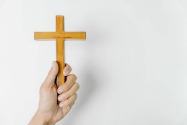Beyaz arka planda bir el tarafından tutulan ahşap bir haç resmi. Haç inancın ve umudun sembolüdür..