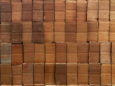 Bir tuğla duvarın fotoğrafı. Tuğlalar sendeleyerek dizilmiş, tuğlaların yatay çizgileri derinlik ve doku hissi yaratıyor.