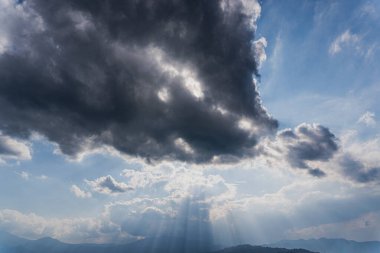 Atmosferik görüntü, gökyüzünün geçici güzelliğini koyu kontrast ve ışık bulutlarıyla birlikte dramatik bir şekilde yakalıyor. bulutlu gökyüzü konsepti