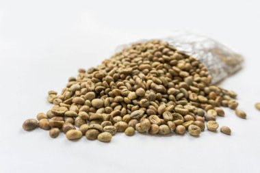 Yeşil kahve çekirdekleri ya da beyaz arka planda izole edilmiş plastik torbadaki çiğ kahve çekirdekleri.