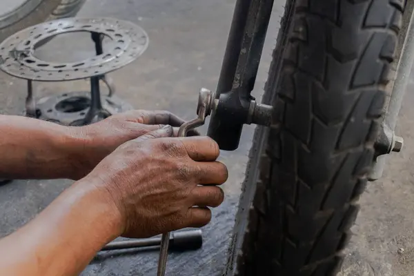 stock image Close-Up Of Mechanic with Oily hand Repairing Damaged black scooter matic.