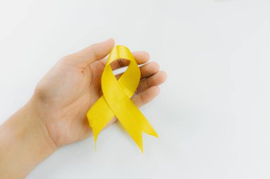 El ele tutuşan sarı kurdele, intihar önleme hareketinin sembolü, beyaz arka plan, intihar önleme ve çocukluk kanseri farkındalığı, Dünya İntihar Önleme Günü konsepti.