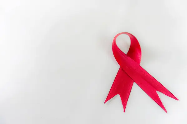 Yakın plan kırmızı kurdele, beyaz arka planda HIV ve Dünya AIDS Günü farkındalığı işareti. Sağlık ve Tıp Konsepti.