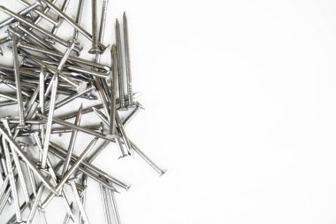 Beyaz arka plana rastgele dağılmış metalik çivi yığını..