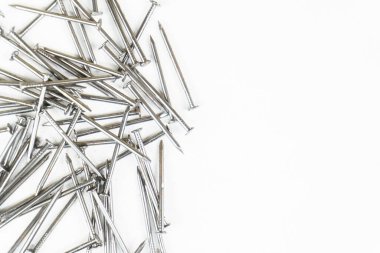 Beyaz arka plana rastgele dağılmış metalik çivi yığını..