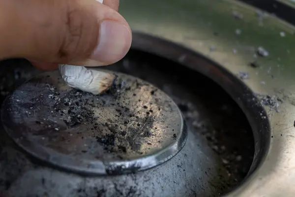 Bir el sigarayı metal bir kül tablasında söndürür..