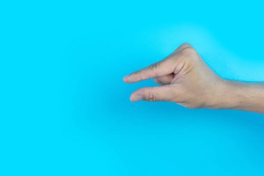 Erkek eli mavi arka planda küçük bir jest yapar.