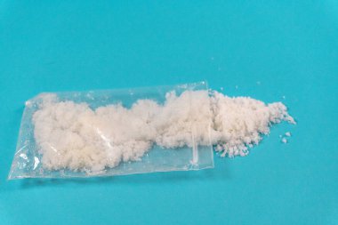 Mavi arka planda beyaz toz ya da meth içeren şeffaf plastik torbalar. Bağımlılık ve kötü alışkanlıklar kavramı.