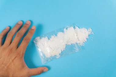 Mavi arka planda beyaz toz ya da meth içeren şeffaf plastik torbalara dokunmaya çalış. Bağımlılık ve kötü alışkanlıklar kavramı.