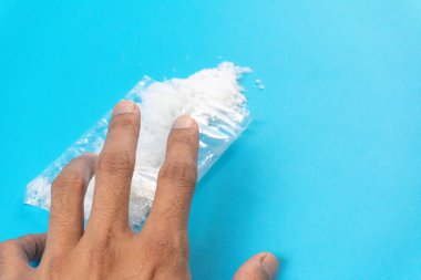 Mavi arka planda beyaz toz ya da meth içeren şeffaf plastik torbalara dokunmaya çalış. Bağımlılık ve kötü alışkanlıklar kavramı.