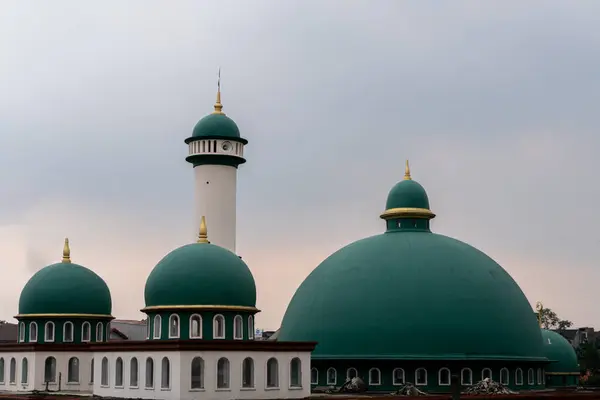 Endonezya 'da bulutlu gökyüzünde yeşil kubbeli bir cami.