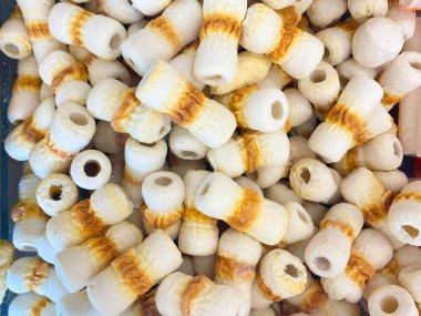 Çok sayıda silindirik, beyaz ve açık kahverengi balık keki ya da kamaboko 'nun yakın plan, yüksek açılı bir çekimi..