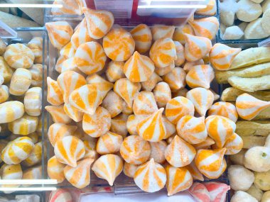 Bir pazarda, beyaz ve turuncu çizgili, donmuş, gözyaşı şeklinde gıda ürünleri sergileniyor..