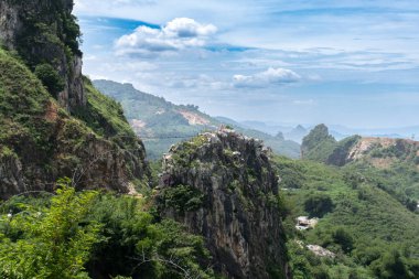 Mavi gökyüzünün altındaki asma köprüyle bağlı kayalık tepelerin manzaralı bir manzarası..