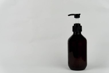 An amber-colored pump bottle is placed against a white backdrop, perfect for showcasing cosmetic or skincare products.