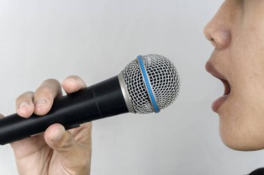 Bir insan mikrofona konuşur. Ağza ve mikrofona odaklanır. Basit bir arkaplana karşı..