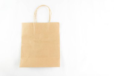 A simple brown paper bag with handles stands isolated on a bright white background.