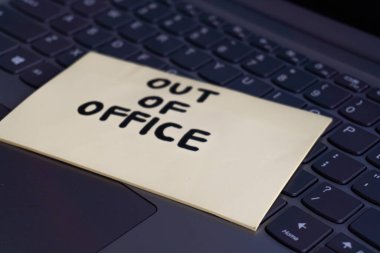A close-up shot of a laptop keyboard with a yellow sticky note that says 