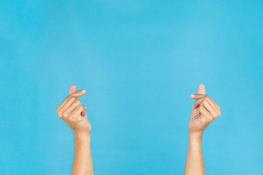 Eller küçük bir kalp hareketi yapıyor, parlak mavi bir arka plana karşı, aşkı ve sevgiyi modern ve modaya uygun bir şekilde ifade ediyor..