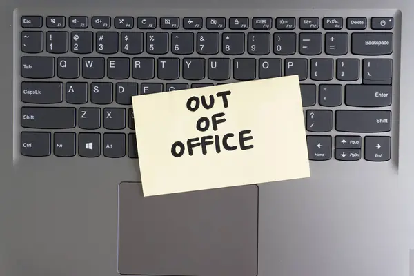 A top-down view of a laptop keyboard with a yellow sticky note that reads 