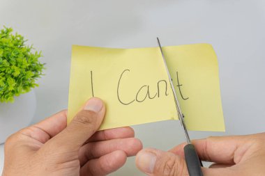 Elinde makas olan eller bitkiyle birlikte sarı yapışkan bir nota 