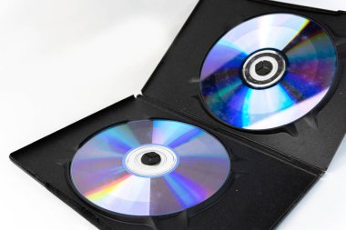 Açık siyah bir kutunun içinde parlak beyaz bir arkaplan üzerine kurulmuş iki CD (CD) yer almaktadır.