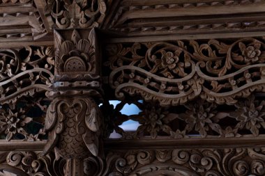 Karmaşık çiçek desenleri ve derin gölgelerle oyulmuş koyu bir ahşap oyma, sanatın derinliğini ve karmaşıklığını vurguluyor..