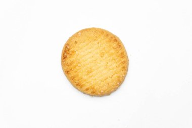 Tek bir yuvarlak tereyağlı kurabiye beyaz bir zemin üzerine konur, basit zarafetini ve şekerli kaplamasını vurgular..