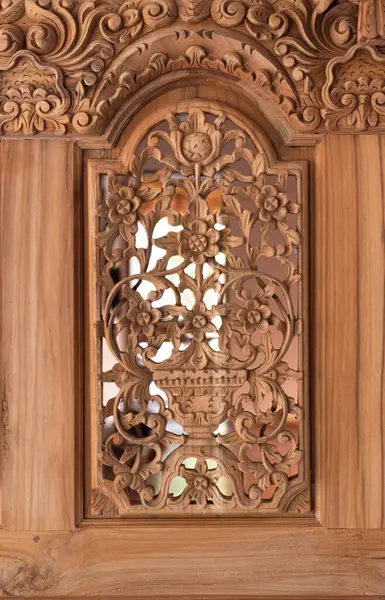 Karmaşık ahşap oyma detaylı bir çekim. Çiçek motifleri ve ahşap bir renkte süslü ve geleneksel sanatsal özellikler..