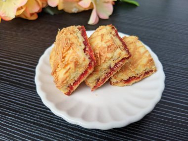 Kahverengi bir tabakta çilekli peynir. Bayram kutlamaları için popüler kurabiyeler (Hari Raya). Hari Raya için ünlü Malezya tatlıları