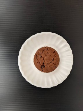 Fındıklı çikolatalı kurabiyelerin siyah arka planda izole edilmiş beyaz çay tabağı üzerindeki odaklanmış görüntüsü. 