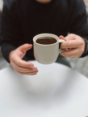 Elinde bir fincan sade kahve tutan adam.