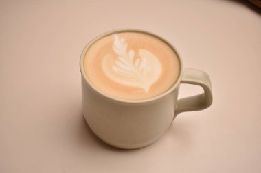 Bej masada bir fincan kapuçino.