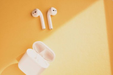 Sarı arka planda beyaz kablosuz kulaklık.