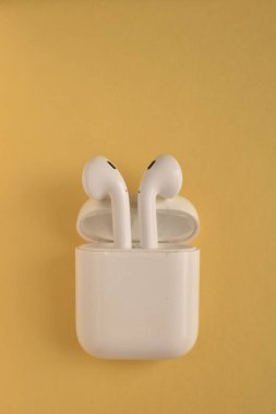 Sarı arka planda beyaz kablosuz kulaklık.