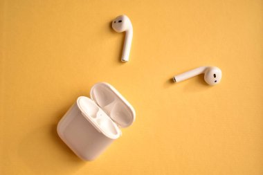 Sarı arka planda beyaz kablosuz kulaklık.