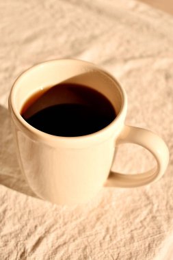 Masanın üzerinde sade, sıcak kahve olan beyaz bir fincan.