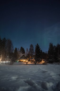 Kuzeydeki loş ışıklar Rovaniemi 'deki evlerin üzerinde, kışın Laponya' da